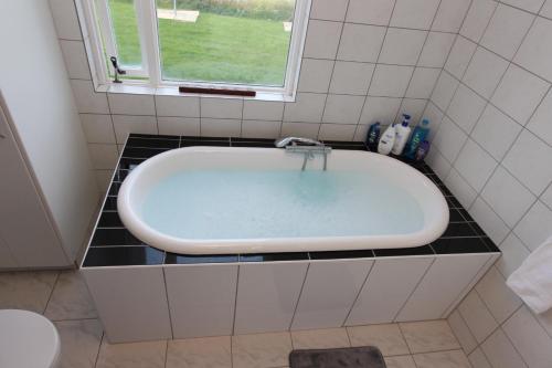 a bath tub in a bathroom with a window at The Viking Country Club in Hjalteyri