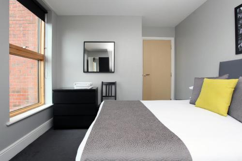 a hotel room with a bed, chair, mirror and window at The City Warehouse Aparthotel in Manchester