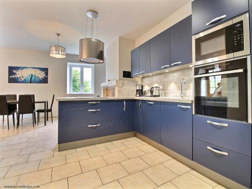 une cuisine avec des armoires bleues et une salle à manger dans l'établissement Gîtes de Pouzelande, à Notre-Dame-de-Sanilhac