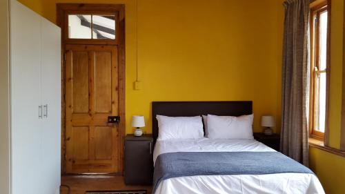 a bedroom with a bed and a yellow wall at Third Rock Guesthouse in Ventersburg
