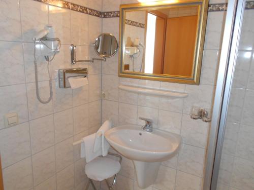 a white bathroom with a sink and a mirror at Hotel Garni Aich in St. Blasien