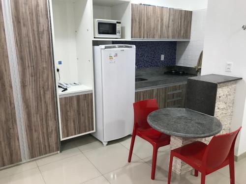 a small kitchen with a table and a refrigerator at Studio Everest Flats in Recife