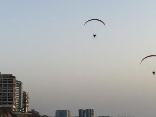 three kites flying in the sky over a city at Raphael Apartments in Herzelia 