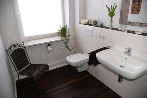 ein weißes Bad mit einem Waschbecken und einem WC in der Unterkunft Hartlef´s Gasthof in Stade