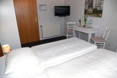1 Schlafzimmer mit 2 Betten, einem Schreibtisch und einem TV in der Unterkunft Hartlef´s Gasthof in Stade