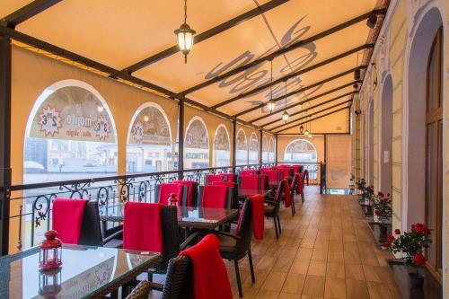 uma sala de jantar com mesas e cadeiras vermelhas em Palace Hotel Polom em Žilina