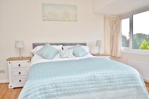 a bedroom with a bed with a blue comforter and a window at Riverside Cottage in Wetherby