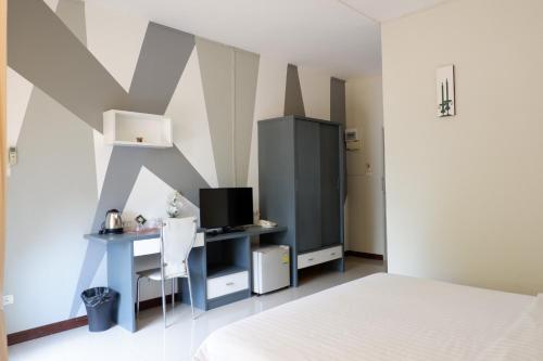 um quarto com uma cama e uma secretária com uma televisão em The Icon service apartment em Si Maha Phot