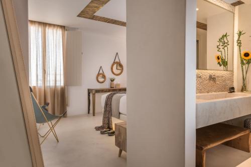 ein Bad mit einem Waschbecken und ein Bett mit einem Spiegel in der Unterkunft White & Co. Exclusive Island Villas in Pirgos