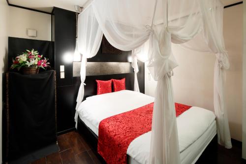 a bedroom with a red and white bed with curtains at Hotel The Lotus Bali (Adult Only) in Kawasaki