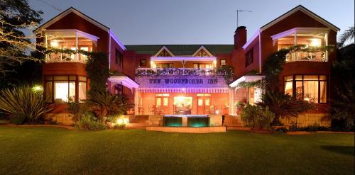 una casa grande con césped delante en The Woodpecker Inn, en Pretoria