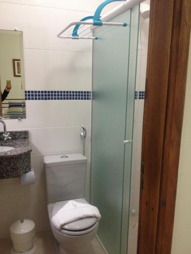 a bathroom with a toilet and a glass shower door at Pousada Ozean in Matinhos