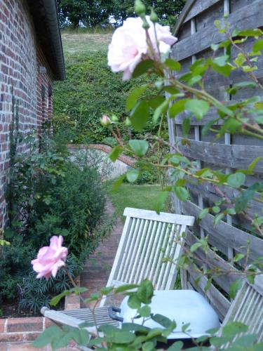 a garden with two white chairs and a pink rose at Gîte de Charme Les Petits Matins Bleus in Sainte-Marguerite-de-Viette