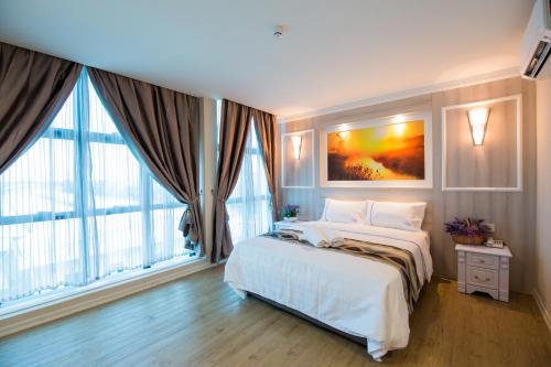 a bedroom with a large bed and large windows at Lavender Inn USJ in Subang Jaya