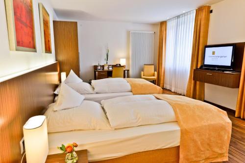a hotel room with a large bed and a television at Hotel Klostergarten in Kevelaer