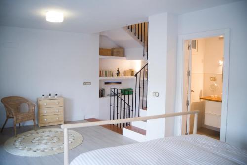 a white bedroom with a staircase and a bed at Triplex Panoramic Ronda in Ronda