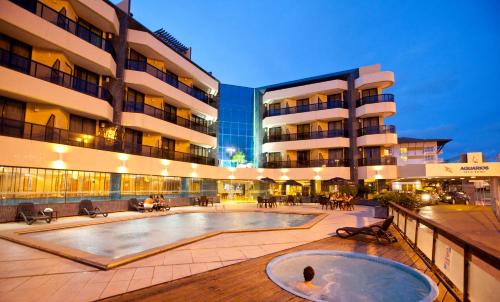 um edifício com piscina em frente a um edifício em Aquarios Praia Hotel em Aracaju