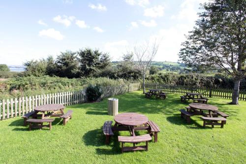 a group of picnic tables and benches in the grass at Fox & Goose, Barrow Gurney by Marston's Inns in Bristol