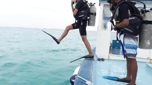 a man standing on the side of a boat in the water at Annama Lodge and Dive in Hoarafushi