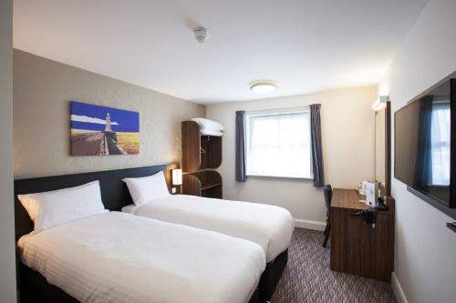 a hotel room with two beds and a television at Lobster Pot, Bridlington by Marston's Inn in Bridlington