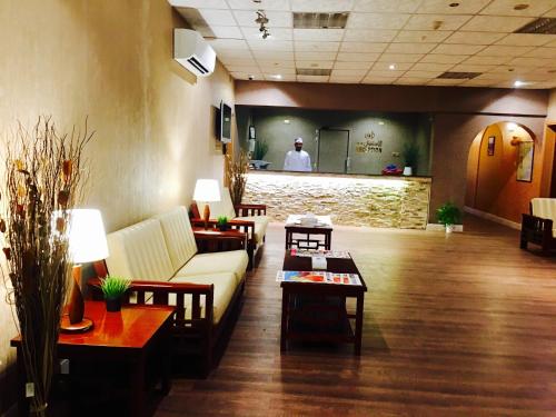 a lobby with a couch and tables and a man in the background at Mutrah Hotel in Muscat