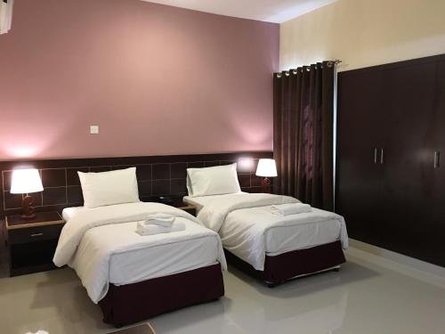 a hotel room with two beds with white sheets at Mutrah Hotel in Muscat