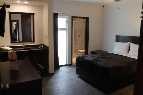 a hotel room with a bed and a sink at Hotel Rincon Real Suites in Durango