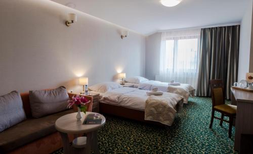 a hotel room with a bed and a couch at Złote Arkady in Częstochowa
