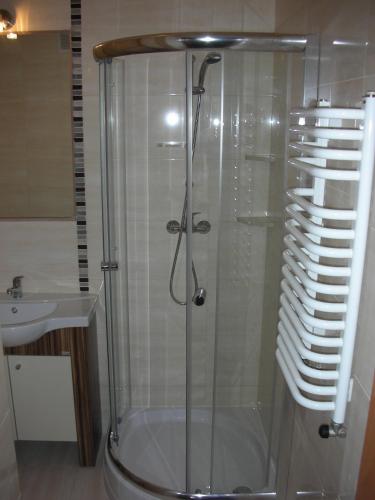 a shower with a glass door next to a sink at Zajazd Kosynier in Węgrzce