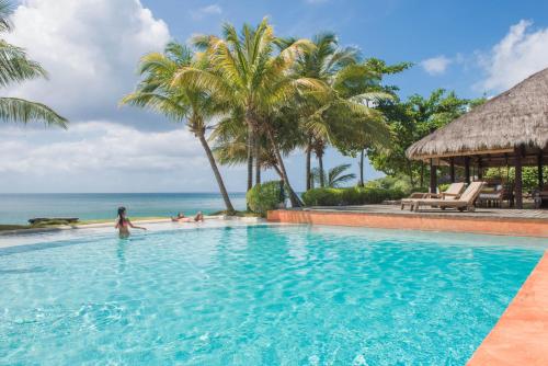 a woman standing in a swimming pool next to the ocean at Laluna Boutique Hotel & Villas in Saint Georgeʼs