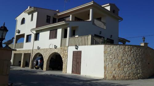 a large white building with a stone wall at Agrepavli Lapithia in Kallepia
