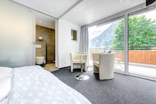 ein Schlafzimmer mit einem Bett und einem Tisch und einem Fenster in der Unterkunft Hotel Lün in Brand
