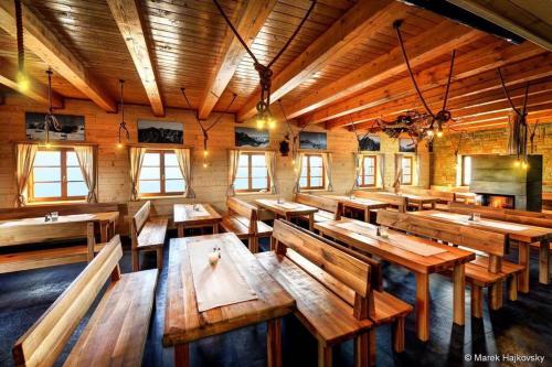 a large room with wooden tables and benches at Horská Chata pod Soliskom in Štrbské Pleso
