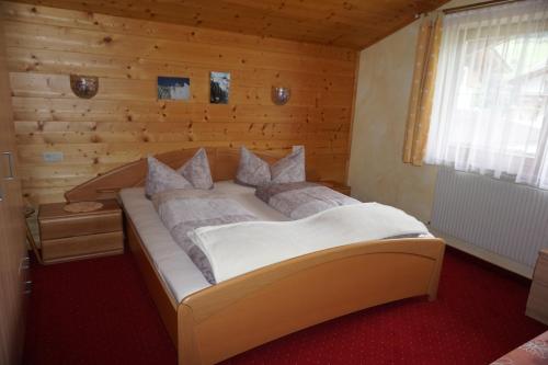 a large bed in a room with a wooden wall at Haus Troger in Milders