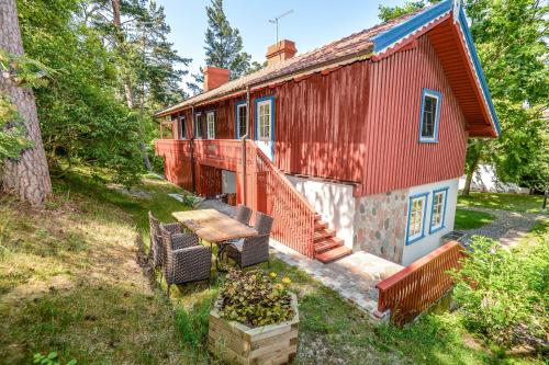 a red house with a table and chairs in front of it at Apartamentai Gėlių Vila in Nida