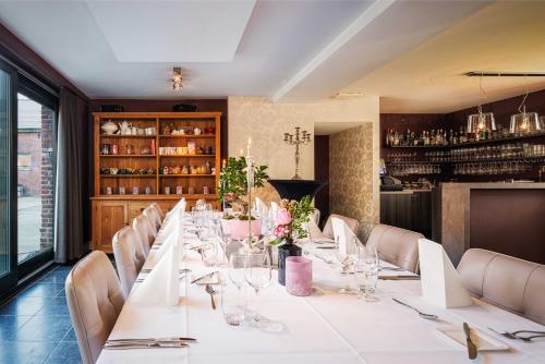 une longue table dans un restaurant avec des tables et des chaises blanches dans l'établissement B&B Bloonwinning, à Hasselt