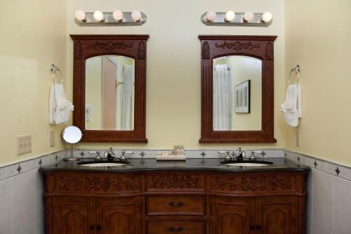 a bathroom with two sinks and two mirrors at La Tourelle Hotel & Spa in Ithaca