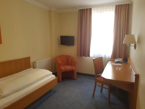 a hotel room with a bed and a desk and a chair at Hotel Garni Keiml in Nuremberg