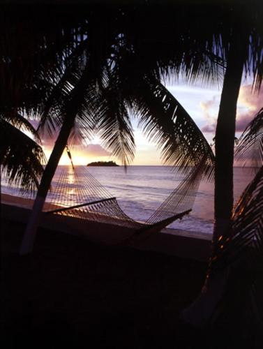 a person in a hammock on the beach at sunset at Villa Beach Cottages in Castries