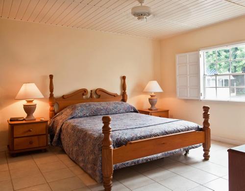 a bedroom with a bed with two night stands and two lamps at Villa Beach Cottages in Castries