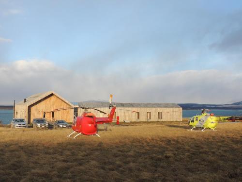 two helicopters parked in a field next to a building at Hotel Simple Patagonia in Puerto Natales