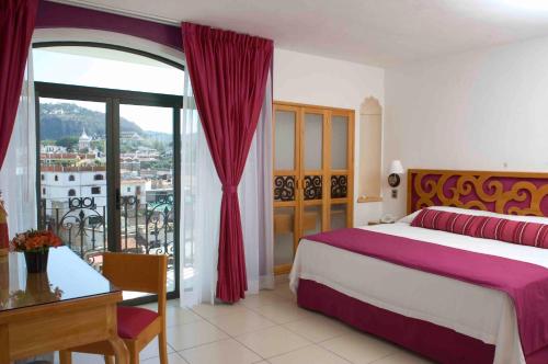 Schlafzimmer mit einem Bett, einem Tisch und einem Fenster in der Unterkunft Boutique Pueblo Lindo in Taxco de Alarcón