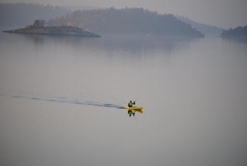 a person on a paddle board in the water at Anfasteröd Gårdsvik - badstugor med loft in Ljungskile