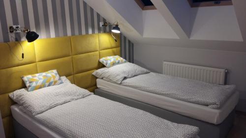2 łóżka pojedyncze w pokoju z żółtymi ścianami w obiekcie Apartament Widokowy w mieście Ustrzyki Dolne