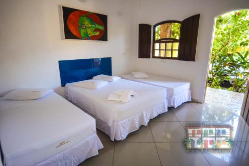 a room with two beds and a window at Pousada Praia do Jabaquara in Paraty