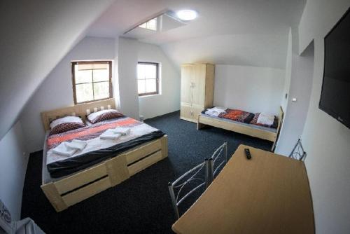 a attic bedroom with two beds and a staircase at Penzion Podyjí in Znojmo
