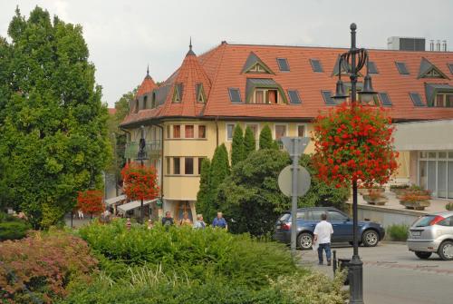 a building with a red roof in a city at Hotel Kalma in Hévíz