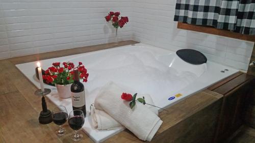 uma banheira com 2 copos de vinho e flores em Pousada Sol Nascente em Visconde de Mauá