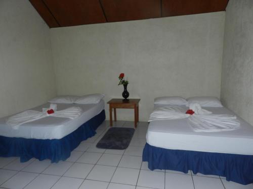 two beds in a room with a table and a vase of flowers at Hostal y Restaurante Rancho Merida in Mérida
