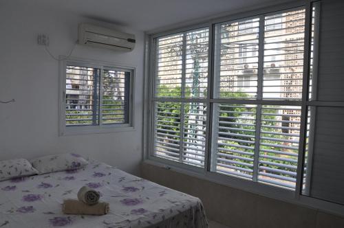 a bedroom with two windows and a bed with a hat on it at Vip Apartment in Bat Yam